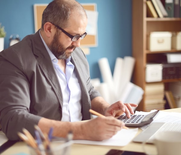 Professional man in office using a calculator