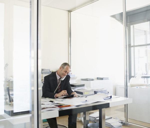 Man on the phone at desk covered in papers