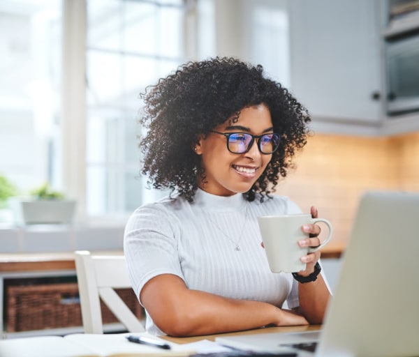 Woman drinking coffee and working on laptop
