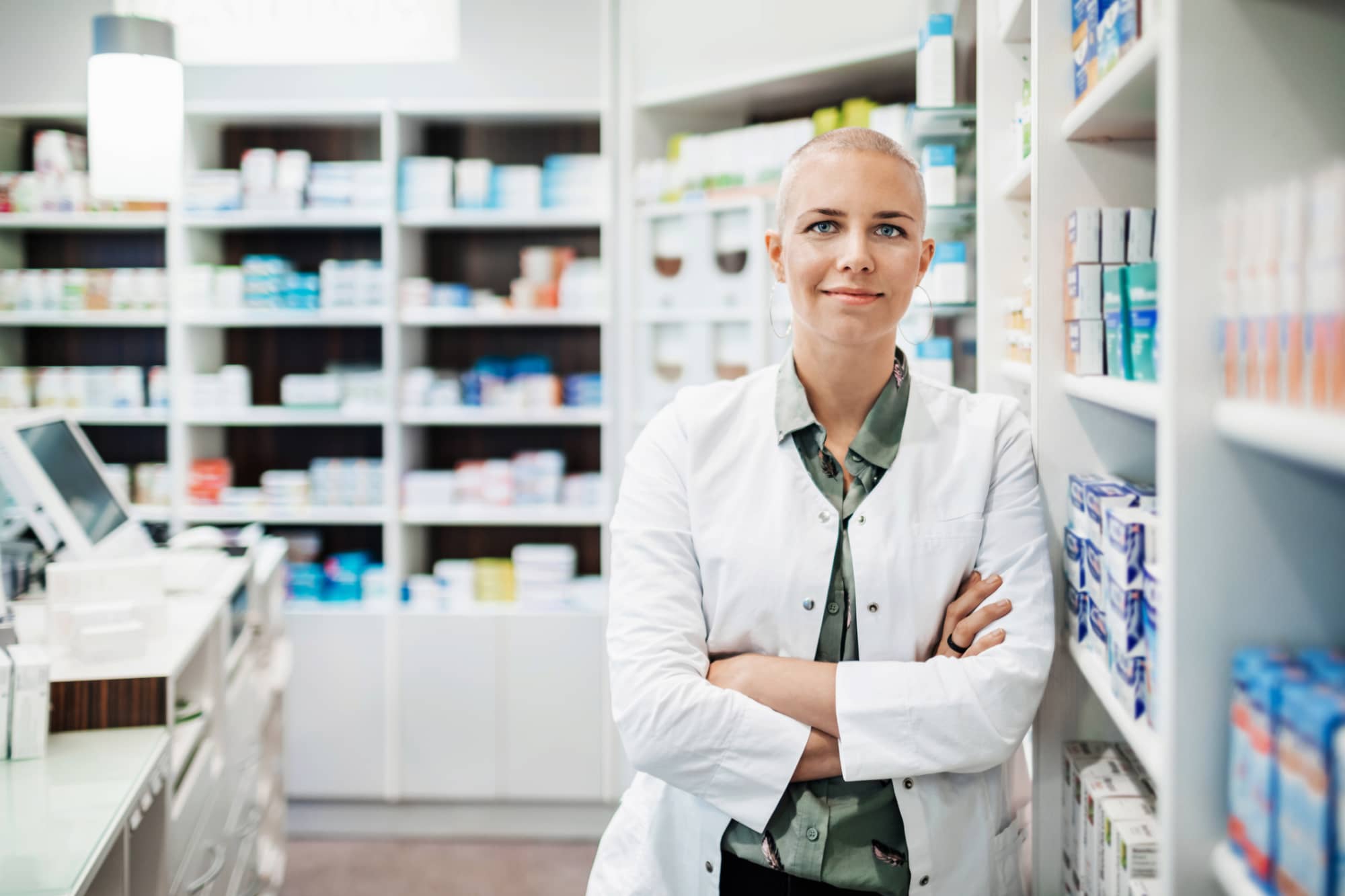 Pharmacist leaning against a shelf in a pharmacy