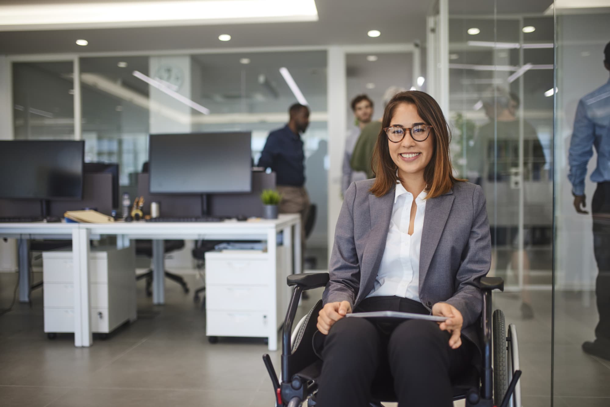 Woman who is using a wheelchair in a professional business office with computers