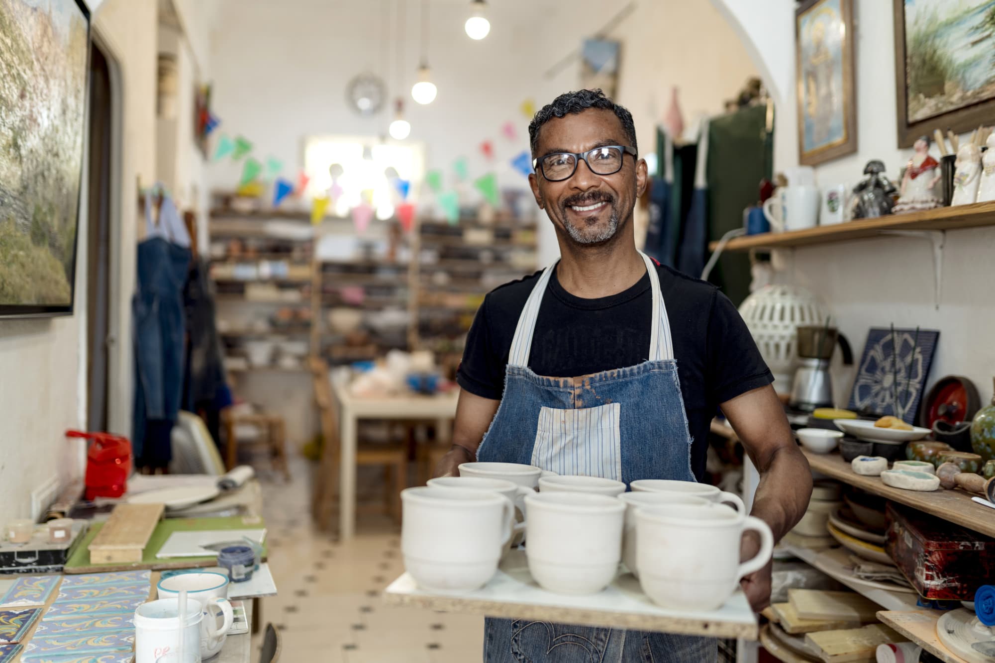 Man holding ceramic mugs in artist workshop