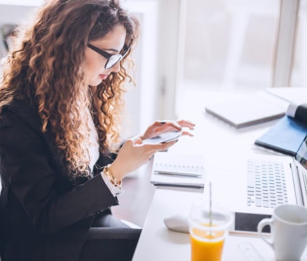Professional woman using a smartphone at a work desk