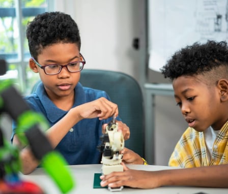 Two young boys working on robotic arm