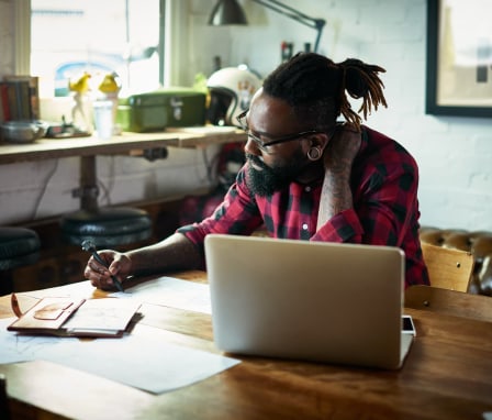 Man sketching at desk in front of laptop