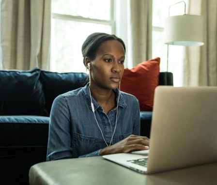 Woman working on a laptop wearing headphones