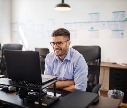 Man smiling at laptop in office
