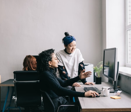 Two people working together on a desktop computer in an office