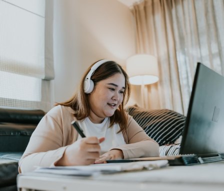 Woman taking notes from laptop at home