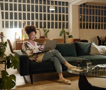 Woman typing on a laptop on her couch at home