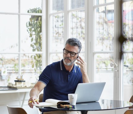 Man talking on phone and working on laptop