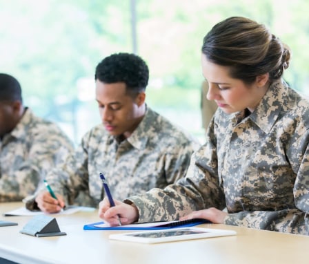 Male and female military cadets take test or take notes during a class at a military academy.