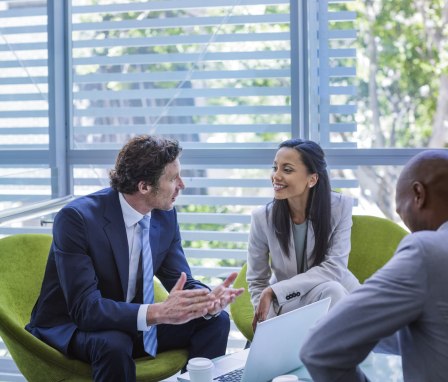 Three corporate professionals talking to each other over coffee