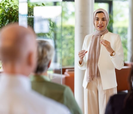 Woman speaking to seated group of colleagues