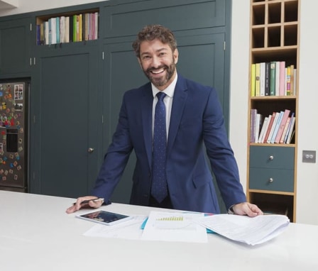 Professionally dressed man standing and smiling in office