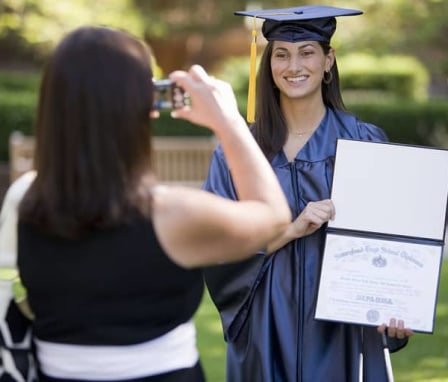 Young woman graduate holding diploma and posing for a picture