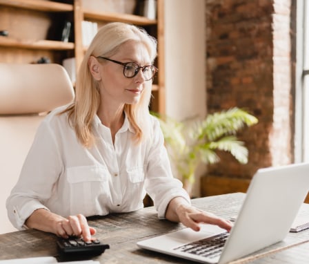 Woman typing on laptop and calculator