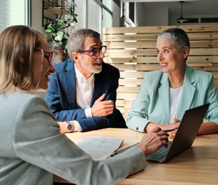 Three business people meeting at a table with a laptop