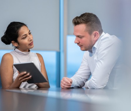 Man and woman talking and looking at tablet