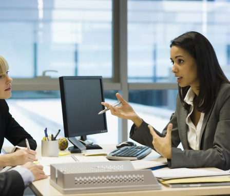 Person at computer talking to two clients