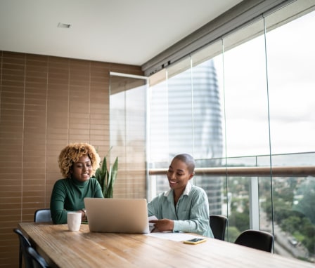 Two women in an office looking at a laptop