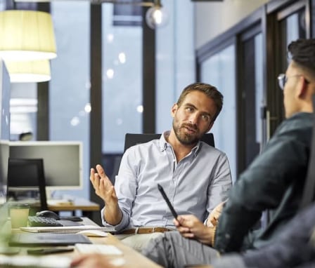 Coworkers talking at a computer desk
