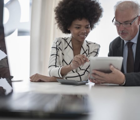 Two people talking and looking at an iPad