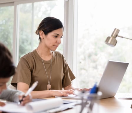Veteran woman on a laptop at home beside kid