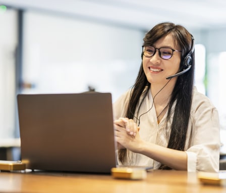 Person on laptop, talking and wearing a headset