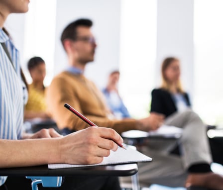 Person taking notes at a desk in a classroom