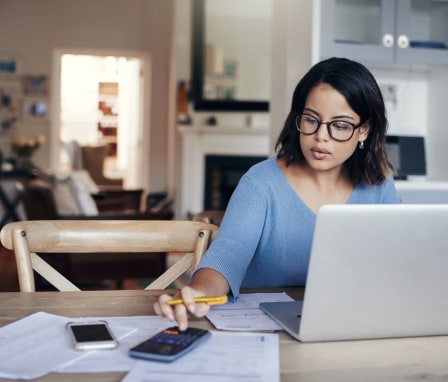 Woman working on laptop and calculator at home