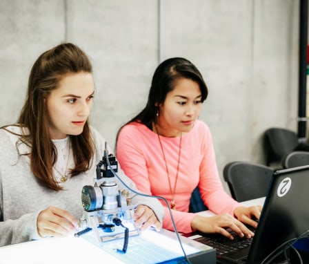 Two students working on a laptop and doing an experiment with technology