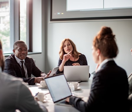 Business professionals talking around a table with their computers
