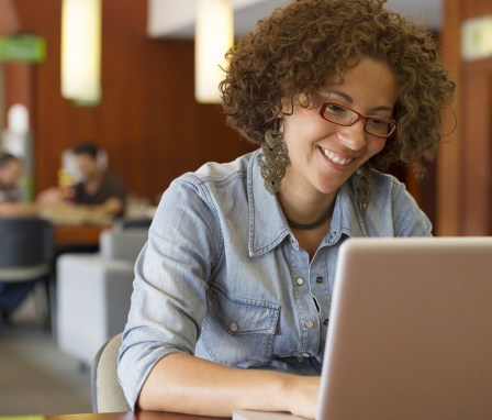 Woman typing while smiling in a library