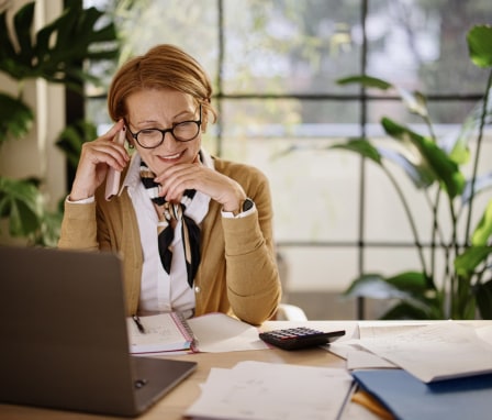 Woman working on laptop with calculator