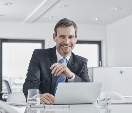 Man smiling and working on laptop in office