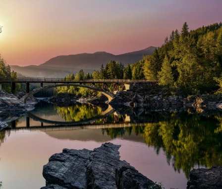 Sunset over a bridge and trees at West Glacier, Montana