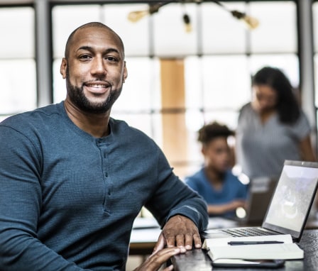 Man working on laptop at home with his family in the background
