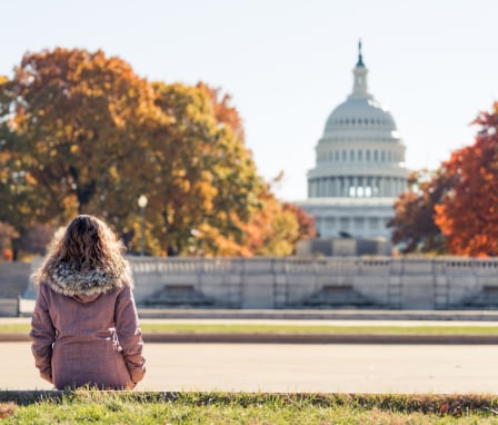 Woman looking at US Capitol Building in autumn