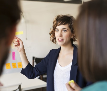 Woman presenting at whiteboard to colleagues