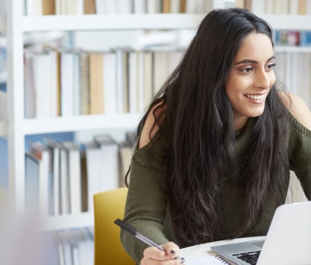 Woman student working on laptop in library