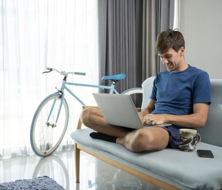 Young man working on a laptop at home on his couch