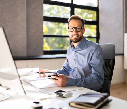 Male accountant writing in a notebook and using a calculator