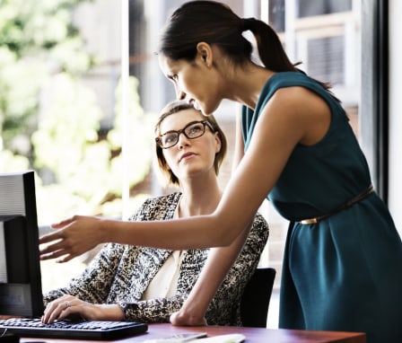 Two women working together on a computer in an office