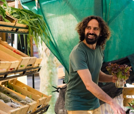 Happy man selling produce at an outdoor market