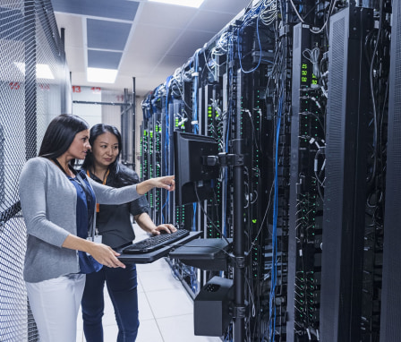 Two women working on a computer in a server room