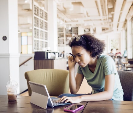 Young woman student on laptop in a cafe