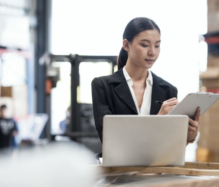 Woman writing on clipboard in a warehouse