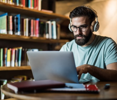 Man studying for a test on his laptop in a library