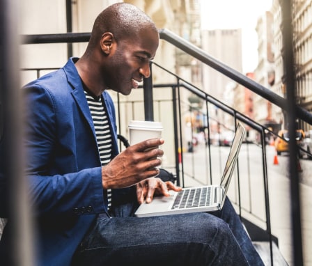 Man working on laptop on house stoop in city